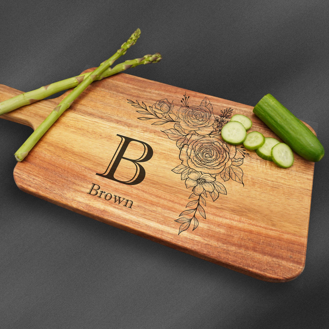 Cutting board with handle and an initial with a last name and flower.