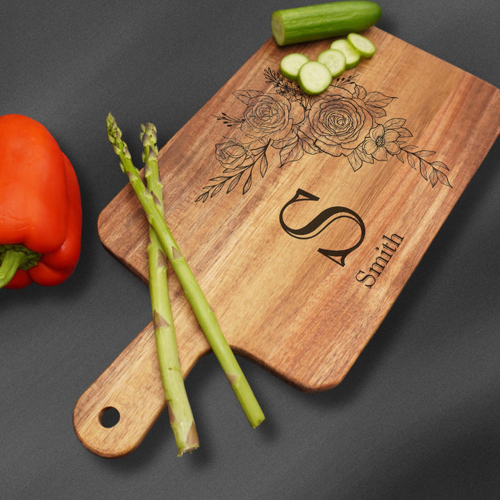 Cutting board and an initial with a last name and flower engraving.