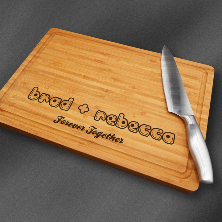 Large personalized cutting board engraved at the base with cute text and a couples names.