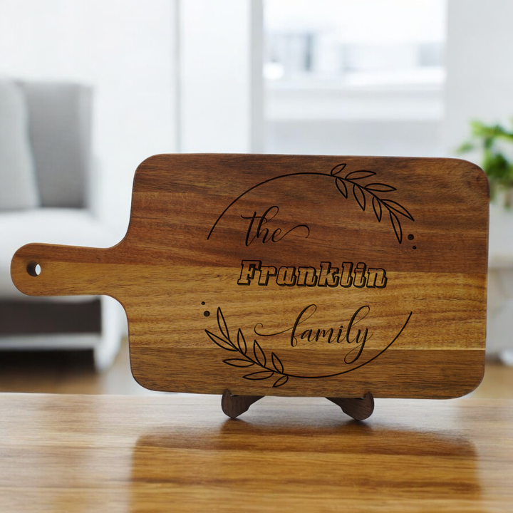 Personalized cutting board with handle and family engraving.